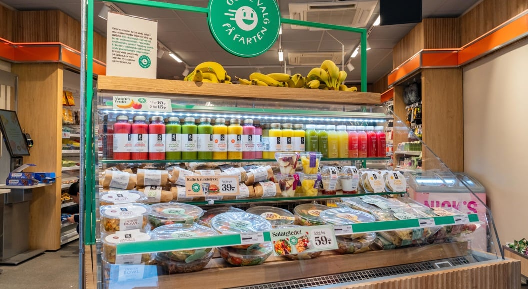 Moderne WHSmith-kiosk på en flyplass som tilbyr bekvemmelighetsartikler, snacks og drikkevarer under levende belysning