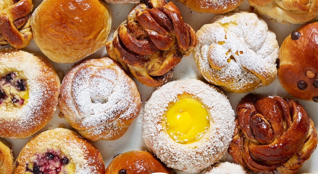 Assorted pastries with various toppings, including powdered sugar and fruit, arranged on a surface with the "Bit Union" logo