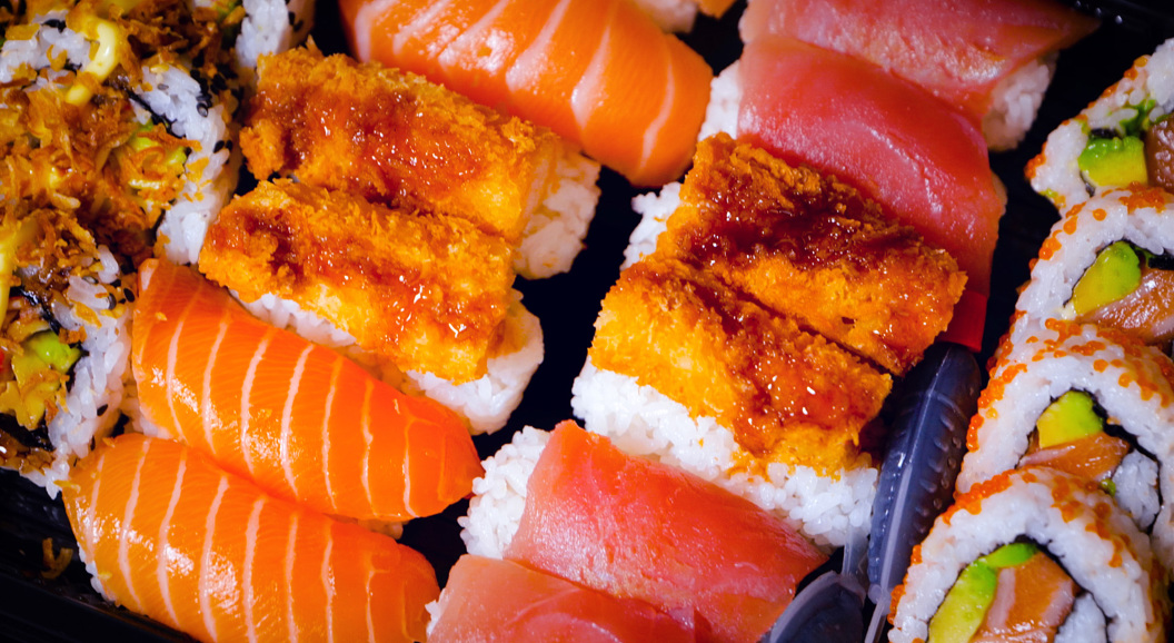 Assorted sushi platter with salmon nigiri, tuna nigiri, crispy shrimp tempura rolls, and fresh avocado rolls