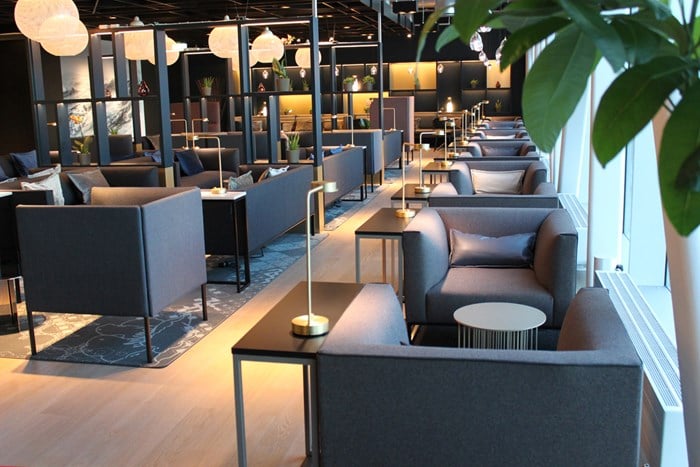 Moderne og elegant lounge med komfortable grå sofaer, små bordlamper, og dekorative elementer, designet for avslapning og sosial interaksjon.