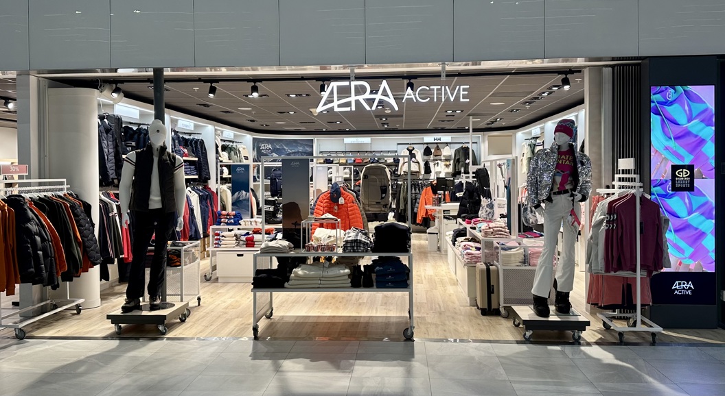 Exterior view of Aera Active clothing store, showcasing mannequins dressed in outdoor apparel and vibrant winter clothing, with well-organized shelves and racks displaying various fashion items inside the modern retail space