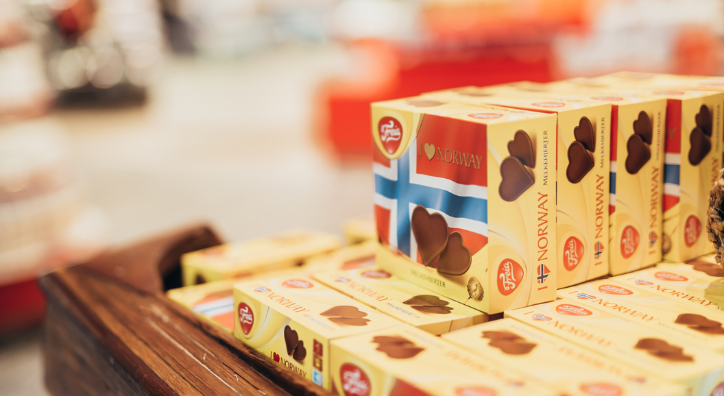 Norwegian chocolate boxes with flags displayed on a wooden shelf in a store