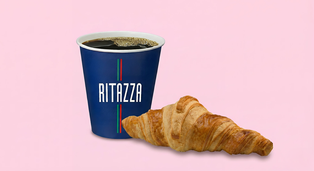 Kopp med svart kaffe og en fersk croissant.