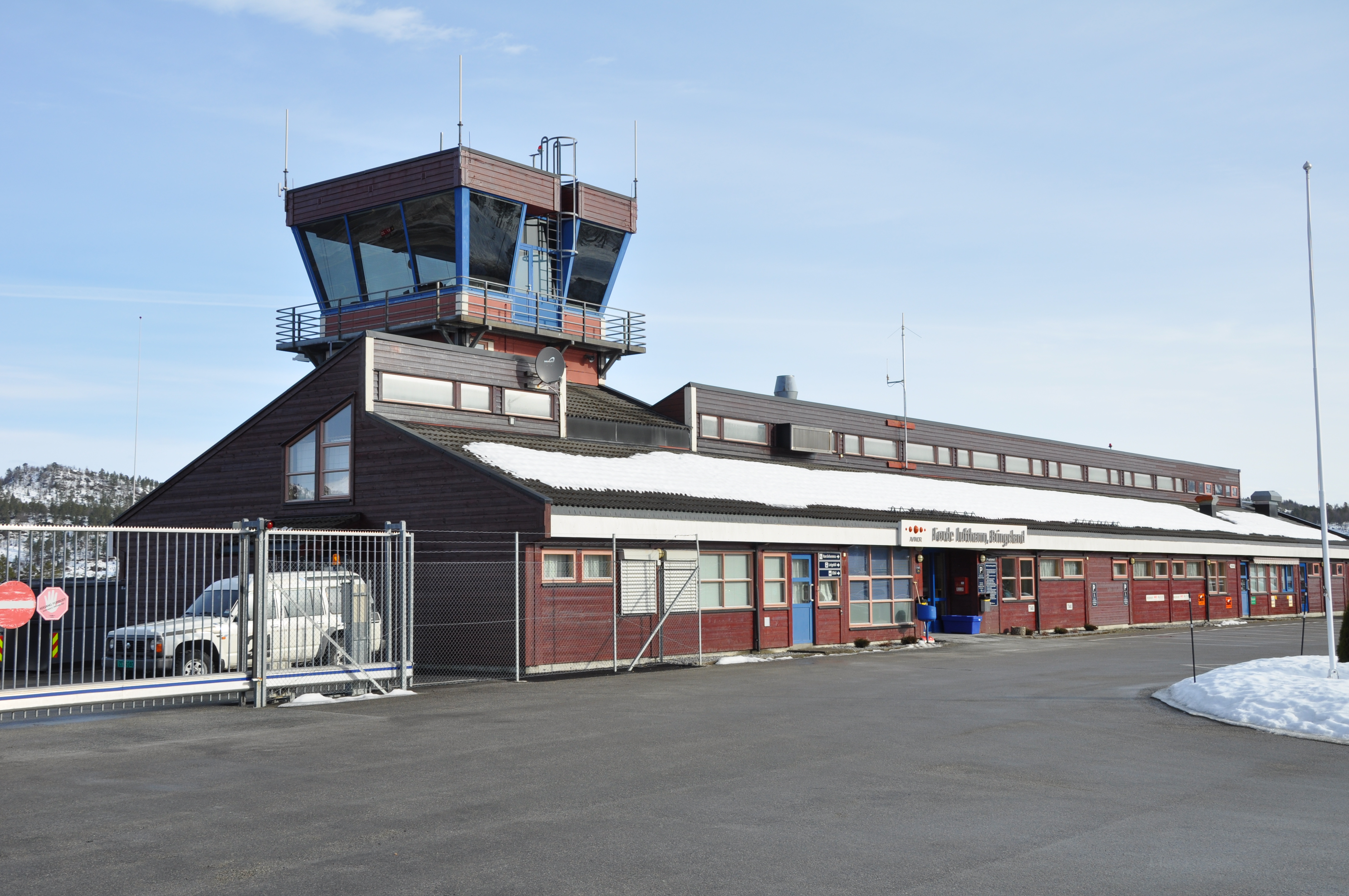 Kontrolltårn ved Førde flyplass i snølandskap, med blå himmel i bakgrunnen.