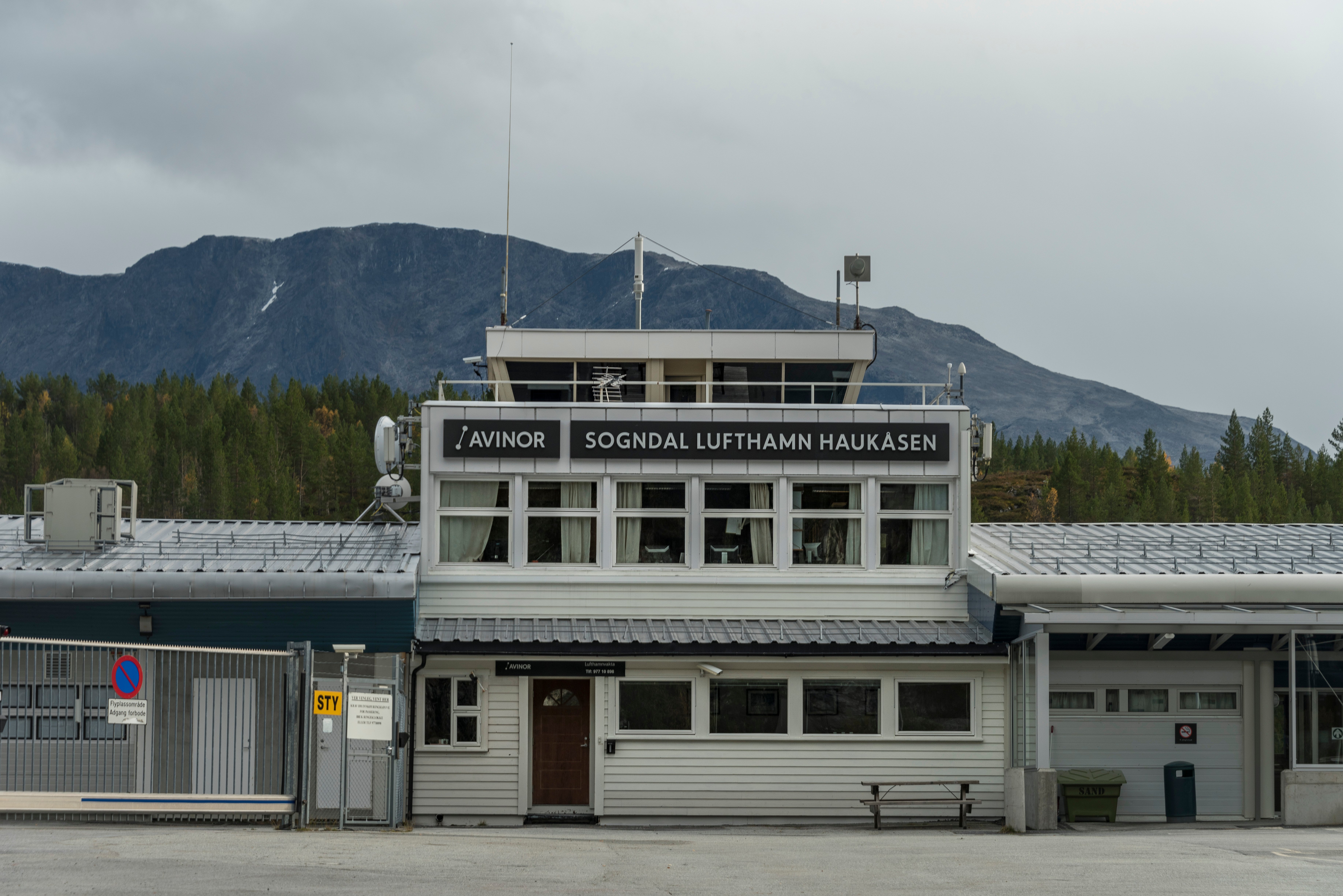 Sogndal lufthavn Haukåsen foran fjellandskap med skog i bakgrunnen, en grå dag.