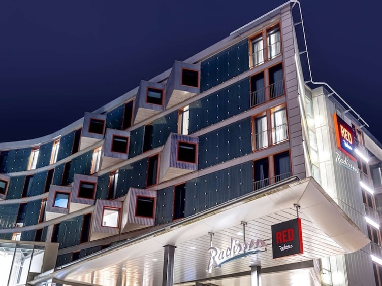 Moderne Radisson RED-hotellfasade om natten med dristig arkitektur og opplyst skilting