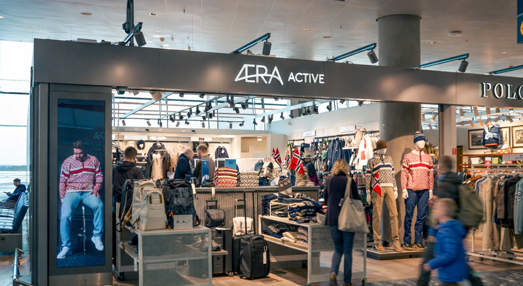 Men's clothing store interior with neatly stacked shirts, jackets on a rack, and a mannequin wearing a beige blazer, showcasing a stylish, organized retail display
