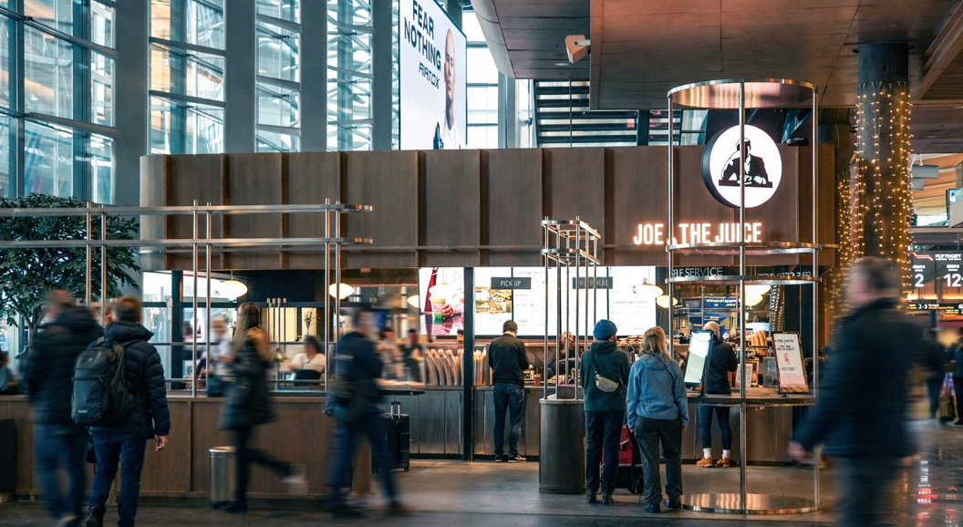 Freshly made sandwich with avocado and tomato paired with a frothy orange juice in a Joe & The Juice branded cup
