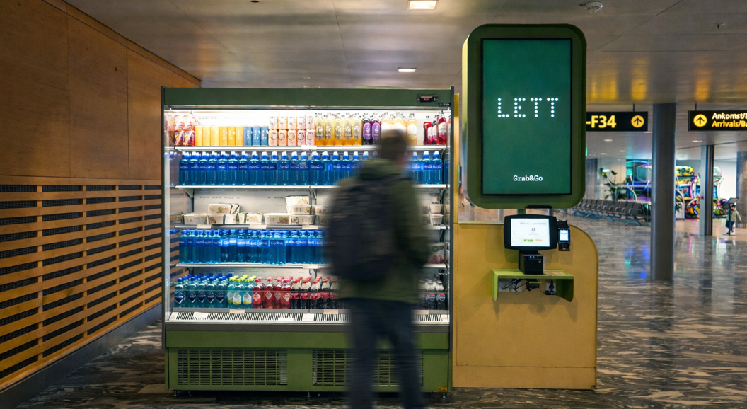 Assorted healthy meals and beverages arranged on a light background, featuring vibrant salads, energy balls, smoothies, fresh juices, and colorful wraps in black bowls