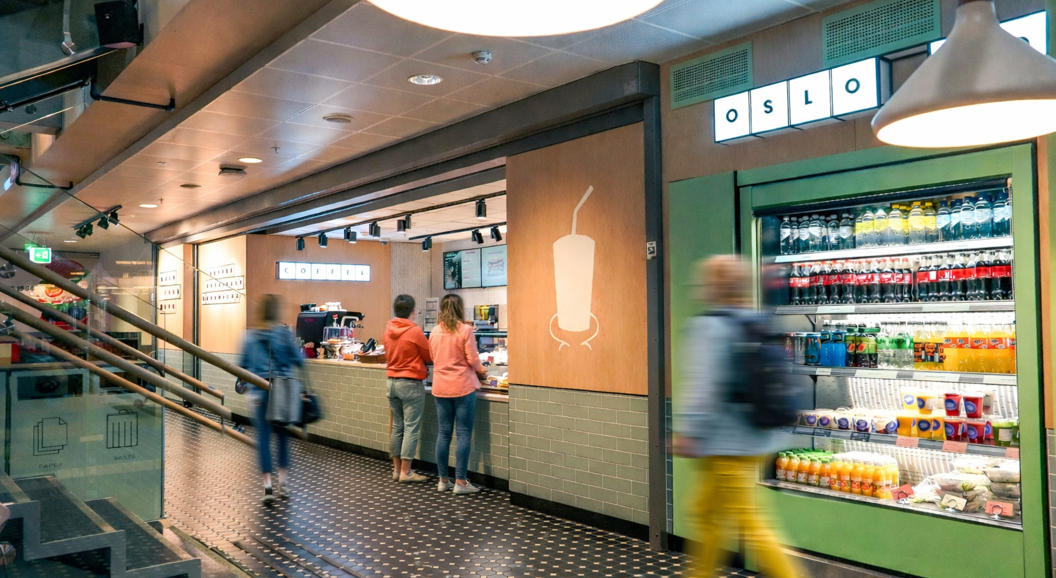 Modern coffee shop counter with a new menu displayed on digital screens, featuring an espresso machine and an assortment of coffee supplies