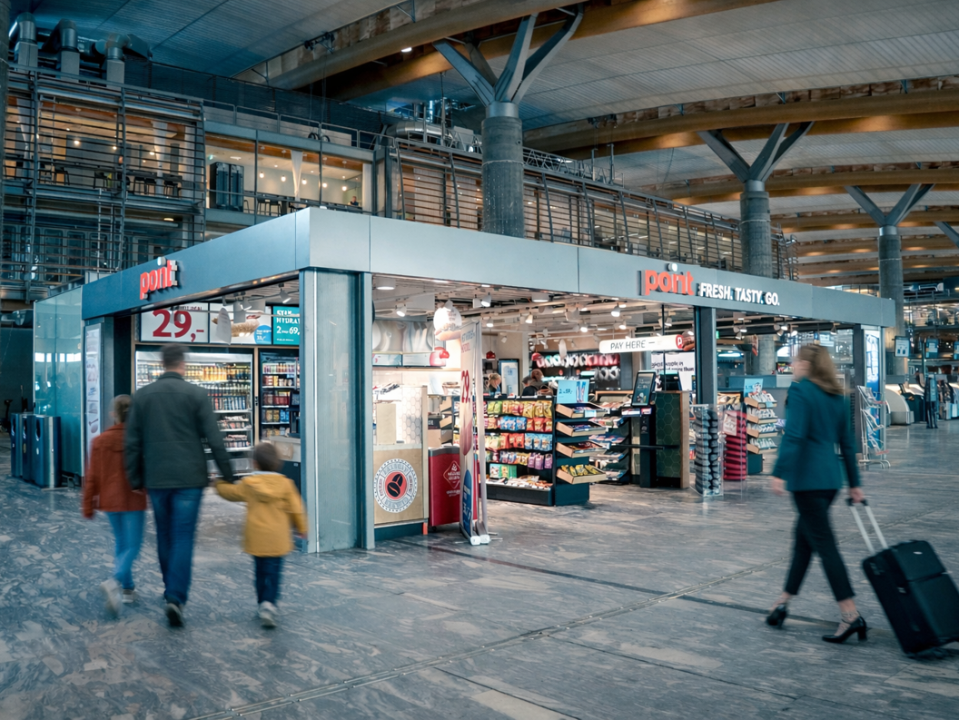 Convenience store kiosk in an airport terminal with snacks, drinks, and magazines displayed