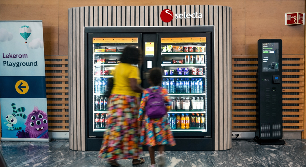 Vending machine stocked with assorted snacks and candy, including chocolate bars and chips, with illuminated keypad