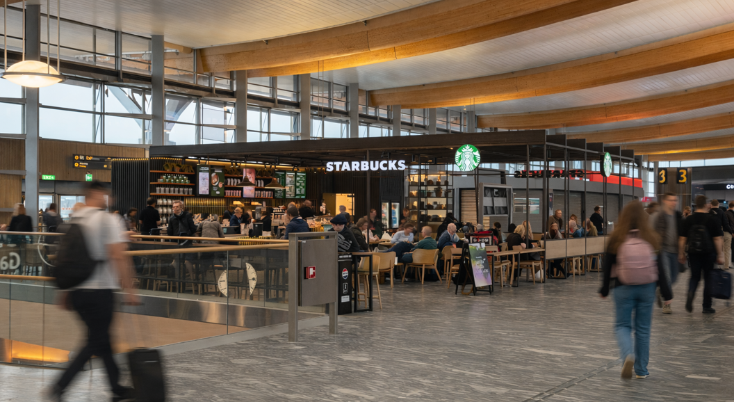 Barista pouring steamed milk into a cup of coffee creating a latte art pattern, held by a person in a green apron