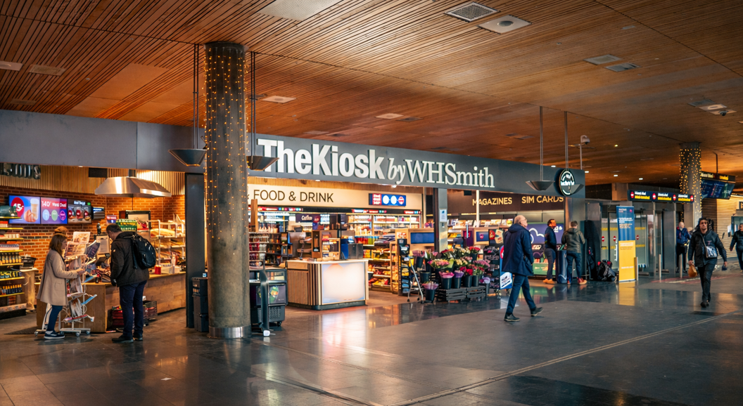 The Kiosk by WHSmith in an airport, featuring a range of snacks, drinks, magazines, and essentials with a modern design and self-service options