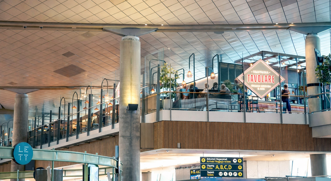 Tavolare Italian Kitchen & Bar sign within a modern shopping complex, featuring glass railings and decorative lighting