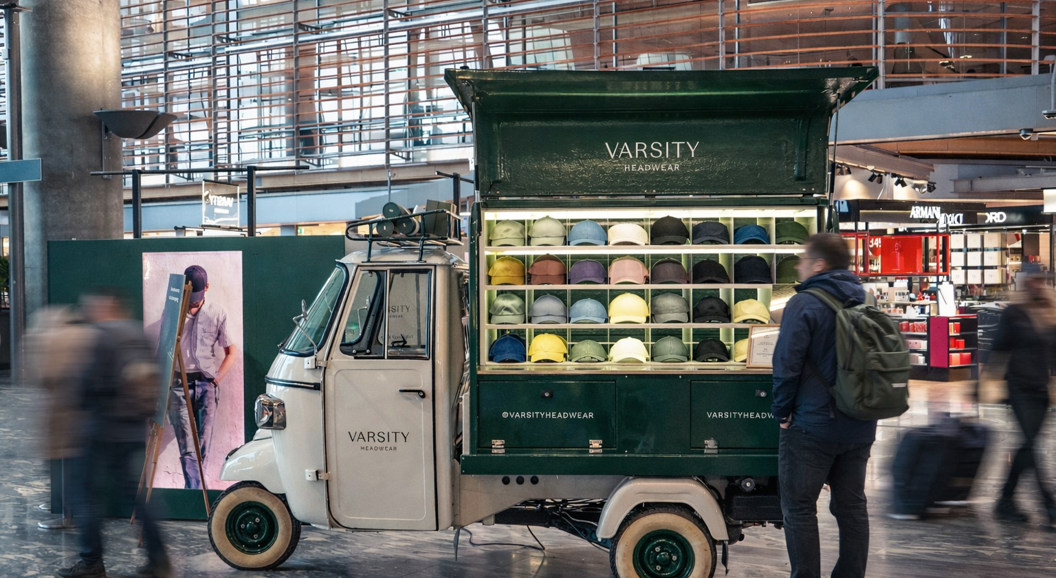 Two stylish caps, one green and one gray, are placed on stacked white concrete blocks with a dark background