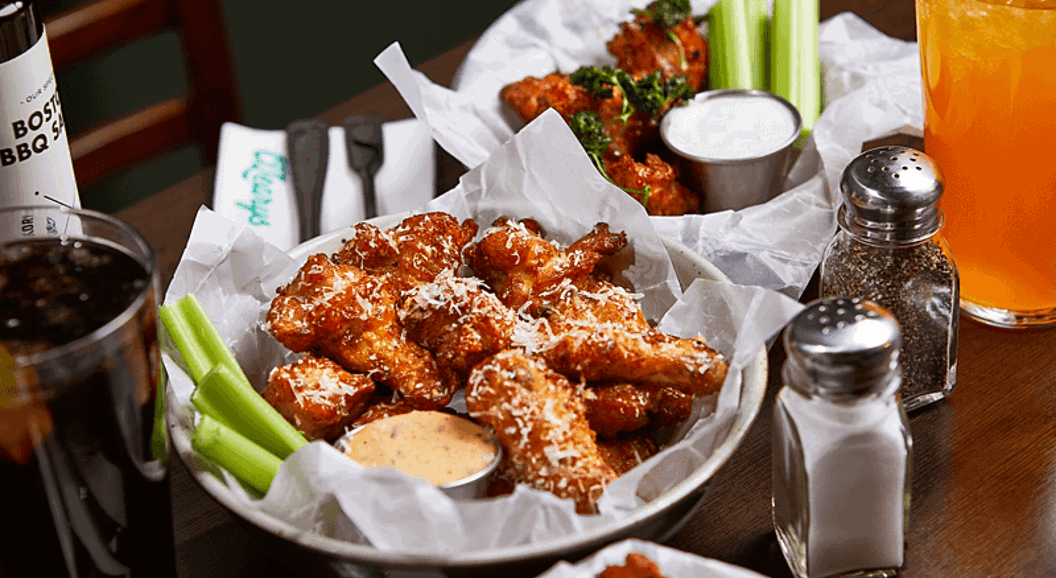 Buffalo wings in a basket with celery and spicy sauce